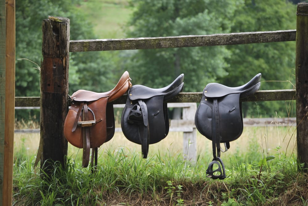 Horse saddles sitting on a fence